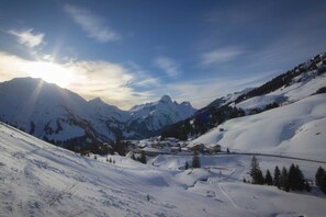 Un paysage montagneux enneigé, avec un petit village niché au fond de la vallée.
