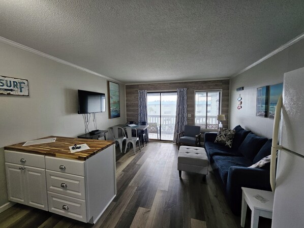 A compact living space with a kitchenette, dining area, and a sofa. - Water View w/ Pool, Top Floor of Elevator Bldg. Beachside Condo (Tybee Island)