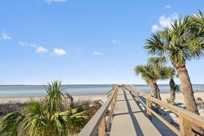 A wooden boardwalk leading to a beach with palm trees and a clear sky. - Water View w/ Pool, Top Floor of Elevator Bldg. Beachside Condo (Tybee Island)