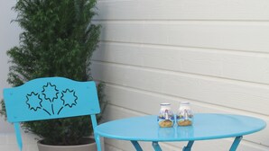Ein blauer Außenbereich mit Sitzgelegenheiten für zwei Personen, inklusive Stühle, einem kleinen Tisch, einem Korbwäscher und einem Blumentopf.