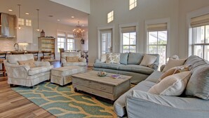 A spacious living room with a large sofa, a coffee table, and a dining area with a chandelier. - Private Cinnamon Shore Home 2-Min. Walk from Pool w/ More Amenities Nearby (Port Aransas)