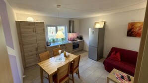 Un espacio habitable compacto con comedor, kitchenette y un sofá rojo.