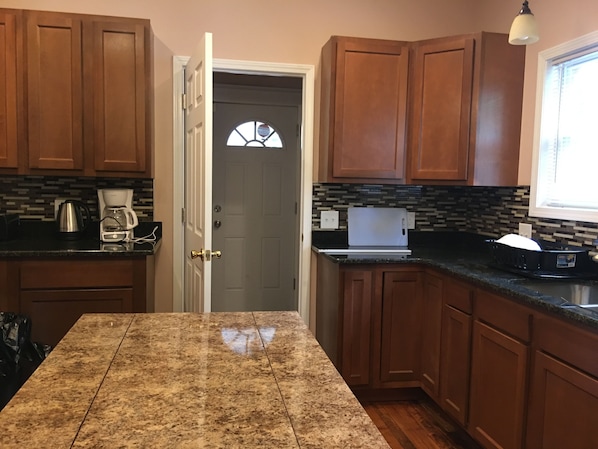 A kitchen with wooden cabinets, a granite countertop, a coffee maker, and a toaster.