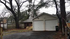 A residential garage with a paved driveway, surrounded by trees and a wooden fence. - Newly updated house close to the Clinic,UH, Case in Cleveland Hts. (Cleveland Heights)