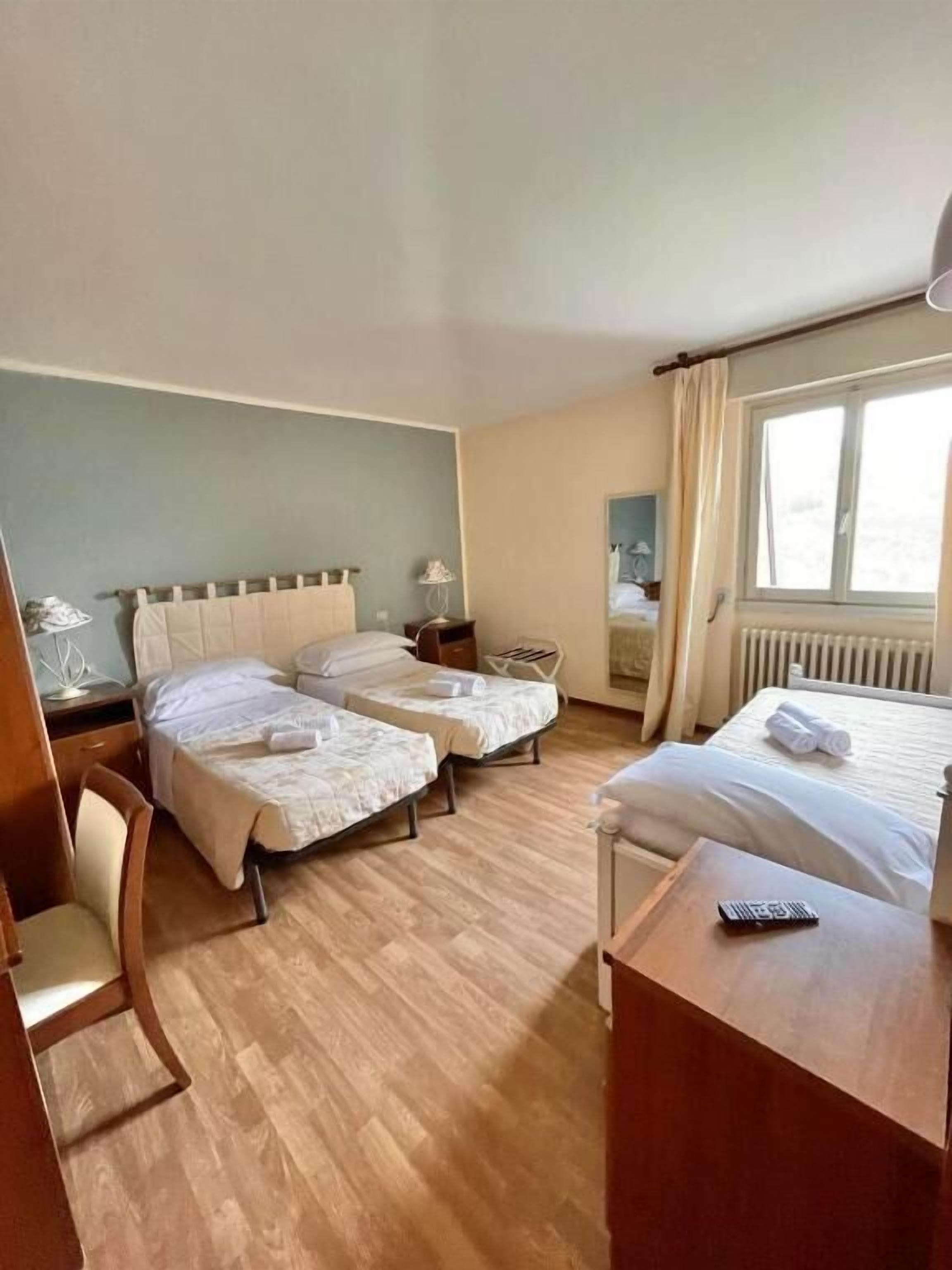 Ein Hotelzimmer mit zwei Betten, einem Schreibtisch, einem Stuhl und einem Fenster.