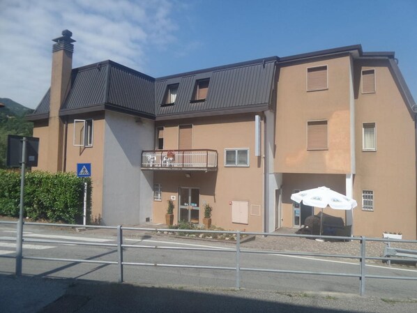 A two-story building with a balcony, a pedestrian crossing sign, and outdoor seating. - Hotel La Sorgente (Plesio)