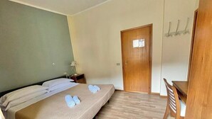 A hotel room with a bed, a wooden door, a small table, and a chair. - Hotel La Sorgente (Plesio)