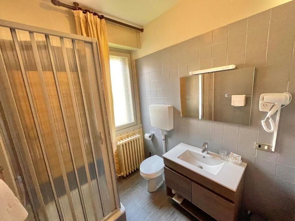 A bathroom with a shower, toilet, sink, and towel rack.