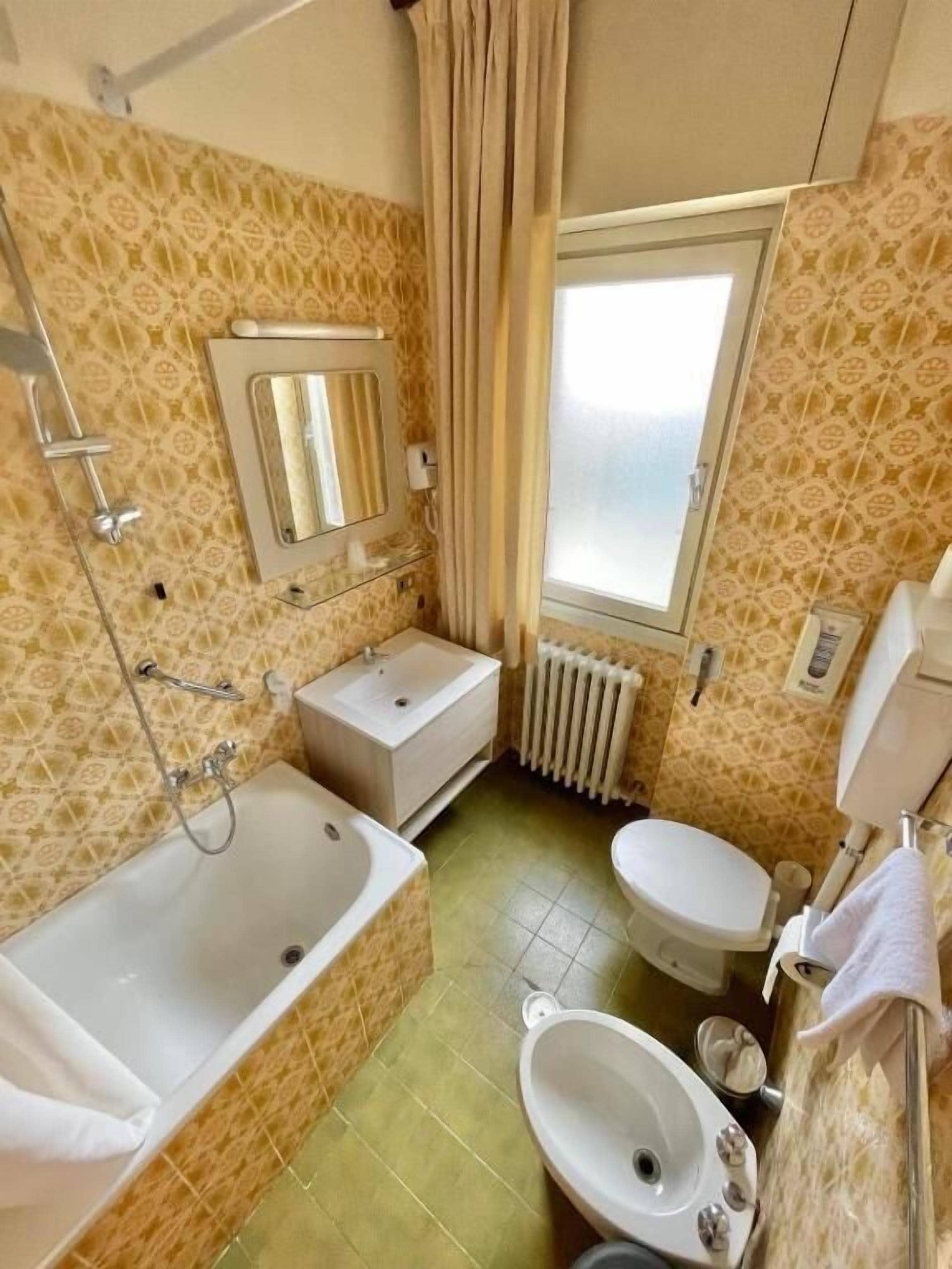 Un bagno compatto con vasca, water e lavandino.