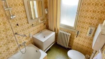 Un bagno compatto con vasca, water e lavandino.