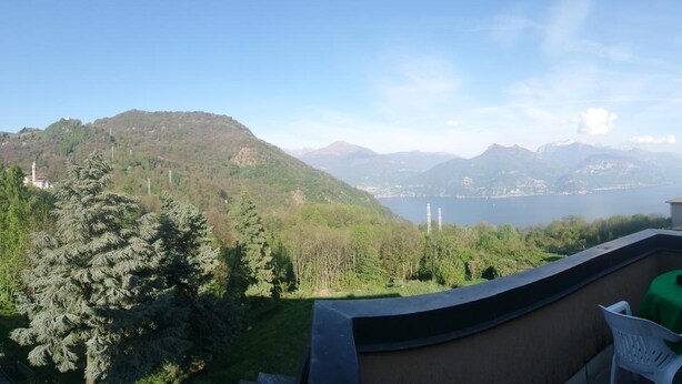 A balcony with a view of a lake, trees, and distant mountains. - Hotel La Sorgente (Plesio)
