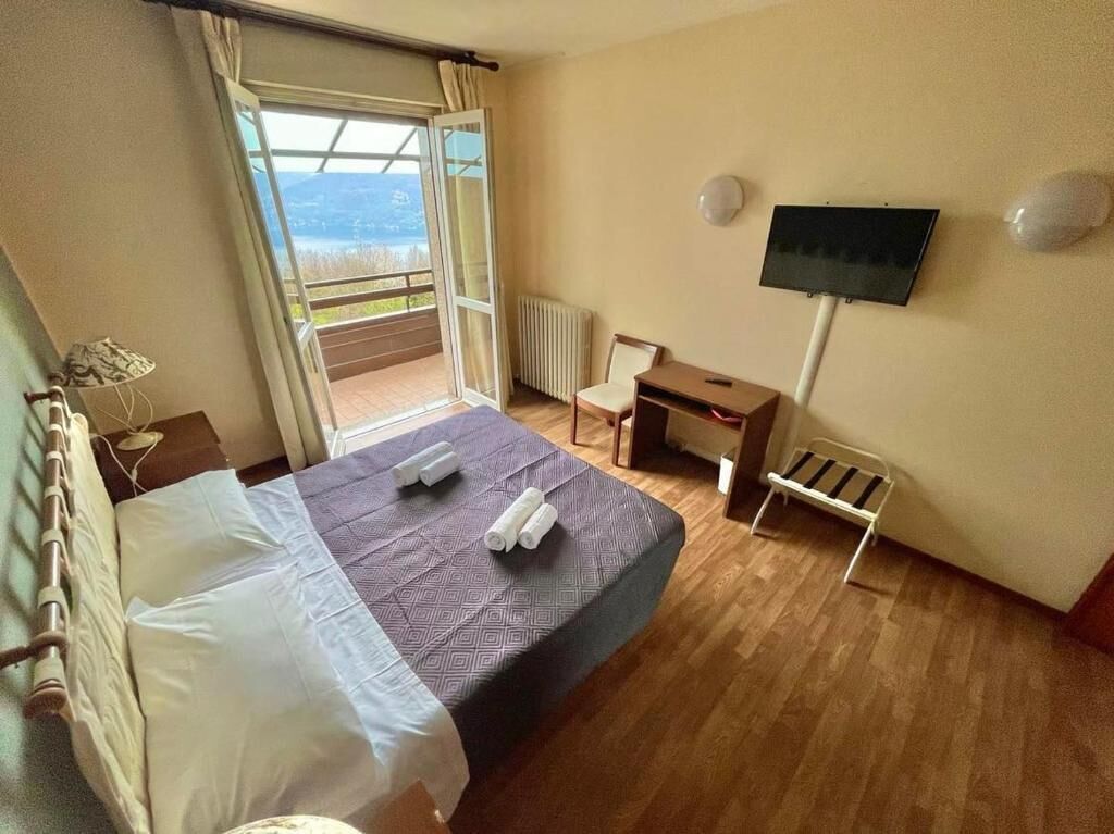 Ein Hotelzimmer mit Bett, Schreibtisch, Stuhl, Fernseher und Blick ins Freie.
