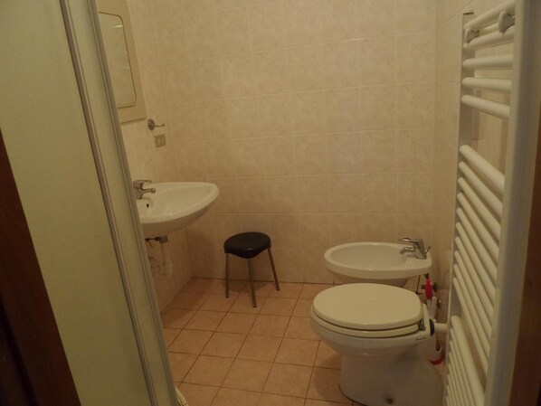 Un baño pequeño con un inodoro, un lavabo y un taburete pequeño.