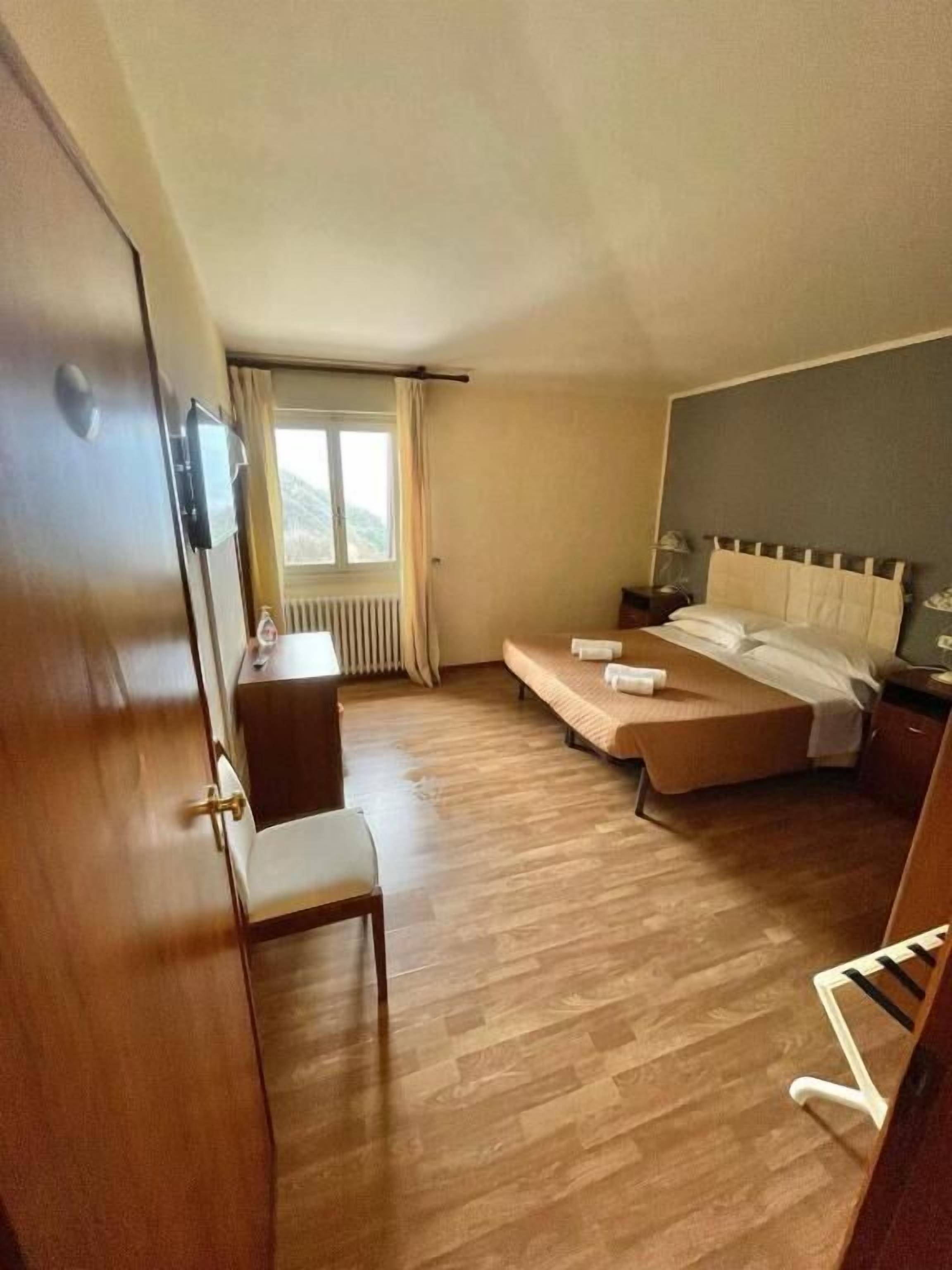 Un dormitorio con cama, una silla, un escritorio y una ventana.