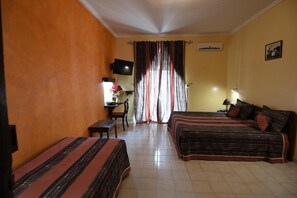 A hotel room with two beds, a desk with a chair, a TV, and a window with curtains. - Hôtel de la Poste (Saint-Claude)