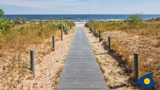 A wooden boardwalk leading to the beach, flanked by sand and vegetation. - Villa Strandperle, Whg. 22 - VS 22 (Heringsdorf)