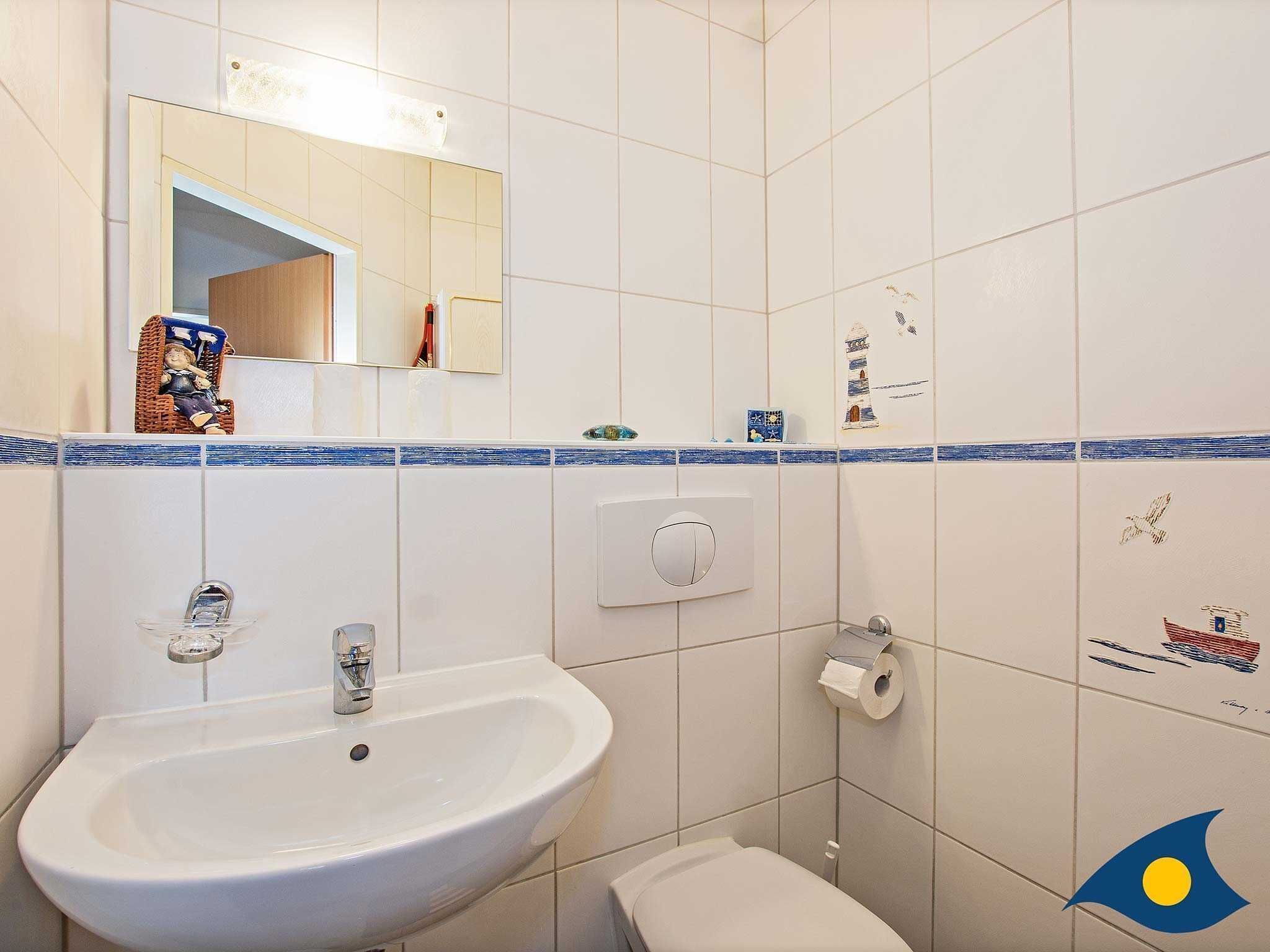 Un baño con lavamanos blanco, inodoro y espejo.