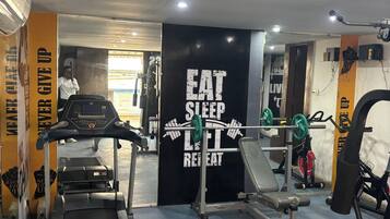 Une salle de sport équipée de tapis de course, d’un banc de musculation et d’une affiche motivante.