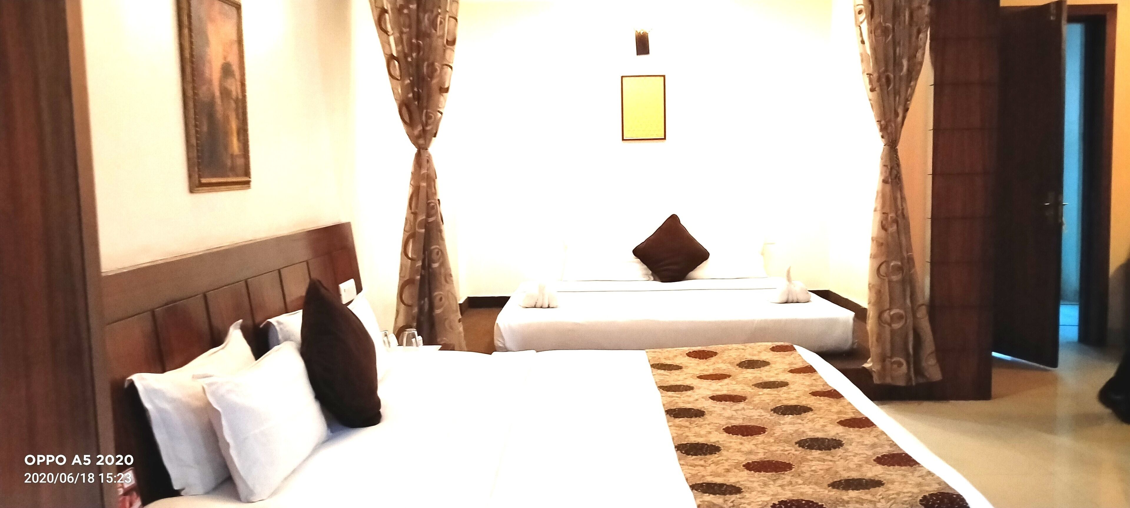 Una camera d'hotel con due letti, una testiera in legno, un tappeto decorato e un quadro appeso al muro.