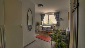 Une pièce comprenant une table à manger, des chaises, un canapé, un tapis rouge et une plante en pot.
