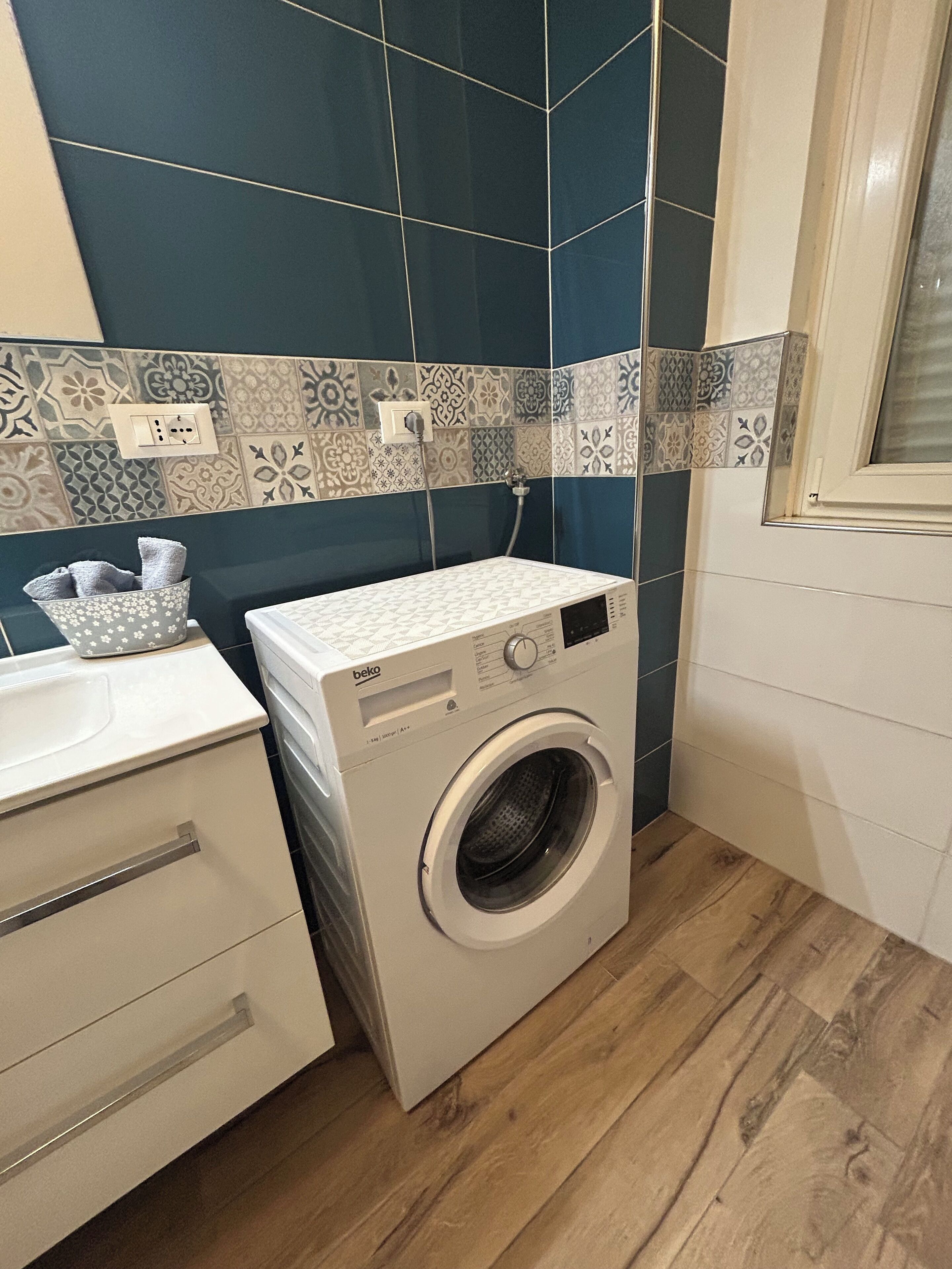Un espace buanderie compact comprenant un lave-linge à chargement frontal, un évier et un porte-serviettes.
