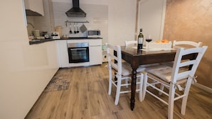 A compact kitchen with a built-in oven, a microwave, and a hanging pot rack.