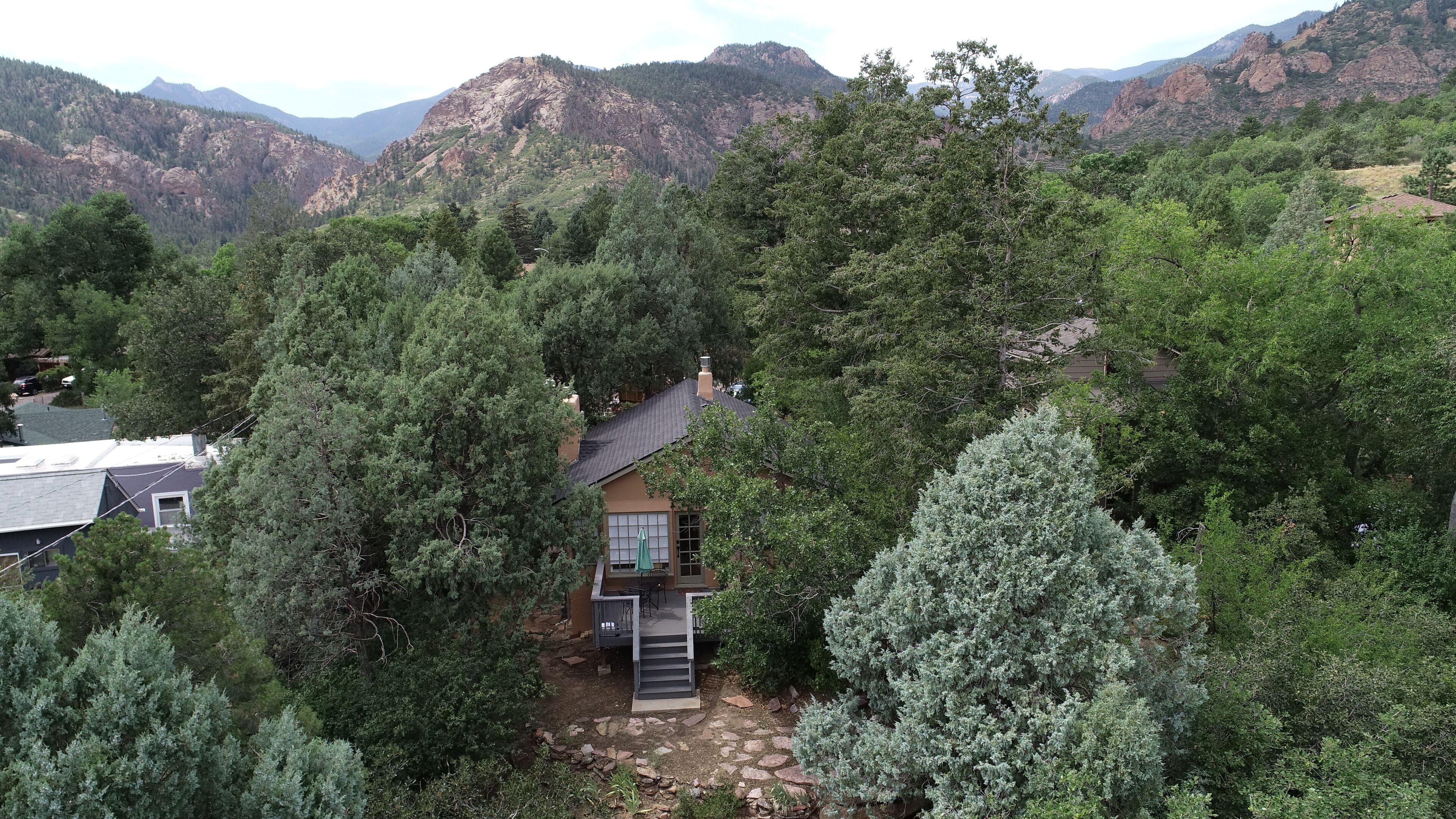 A house surrounded by dense forest with a mountain backdrop.