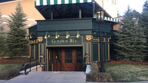A building with a green and white striped awning, a sign reading "Golden Bee Established 1961", and a "Welcome" sign above the entrance.