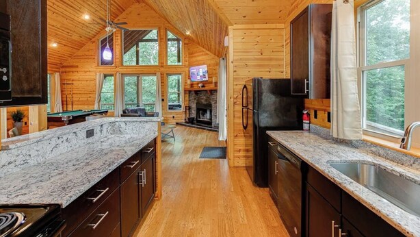 A modern kitchen with wooden walls, granite countertops, and a central island.