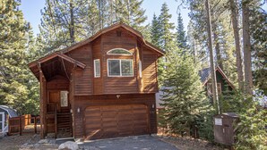 A two-story log cabin with a garage, surrounded by a forest. - Sherman by Hauserman Rentals (Tahoma)