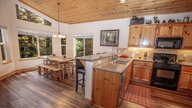 A spacious kitchen with wooden cabinets, a granite countertop, and a large island. - Sherman by Hauserman Rentals (Tahoma)