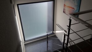 Una escalera con barandilla de metal, una puerta de vidrio esmerilado y un cuadro en la pared.