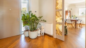 A modern interior with a wooden floor, a white door, and a dining area with a table and chairs. - Villa Modigliani - Casarano (Casarano)