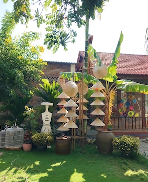A garden with various plants, a birdcage, and a decorative structure with conical elements.