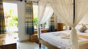 A bedroom with a four-poster bed, a wooden headboard, and a view of greenery outside. - May Bungalow (Mui Ne)