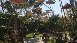 A garden pathway with hanging conical umbrellas, potted plants, and a brick-tiled walkway. - May Bungalow (Mui Ne)