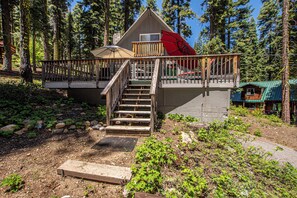 A cabin with a wooden deck, a staircase, and a small porch. - Hillhouse by Hauserman Rental Group (Homewood)