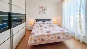 Een moderne slaapkamer met een bed, twee nachtkastjes, een raam met gordijnen en een muur met een vlinder schilderij.