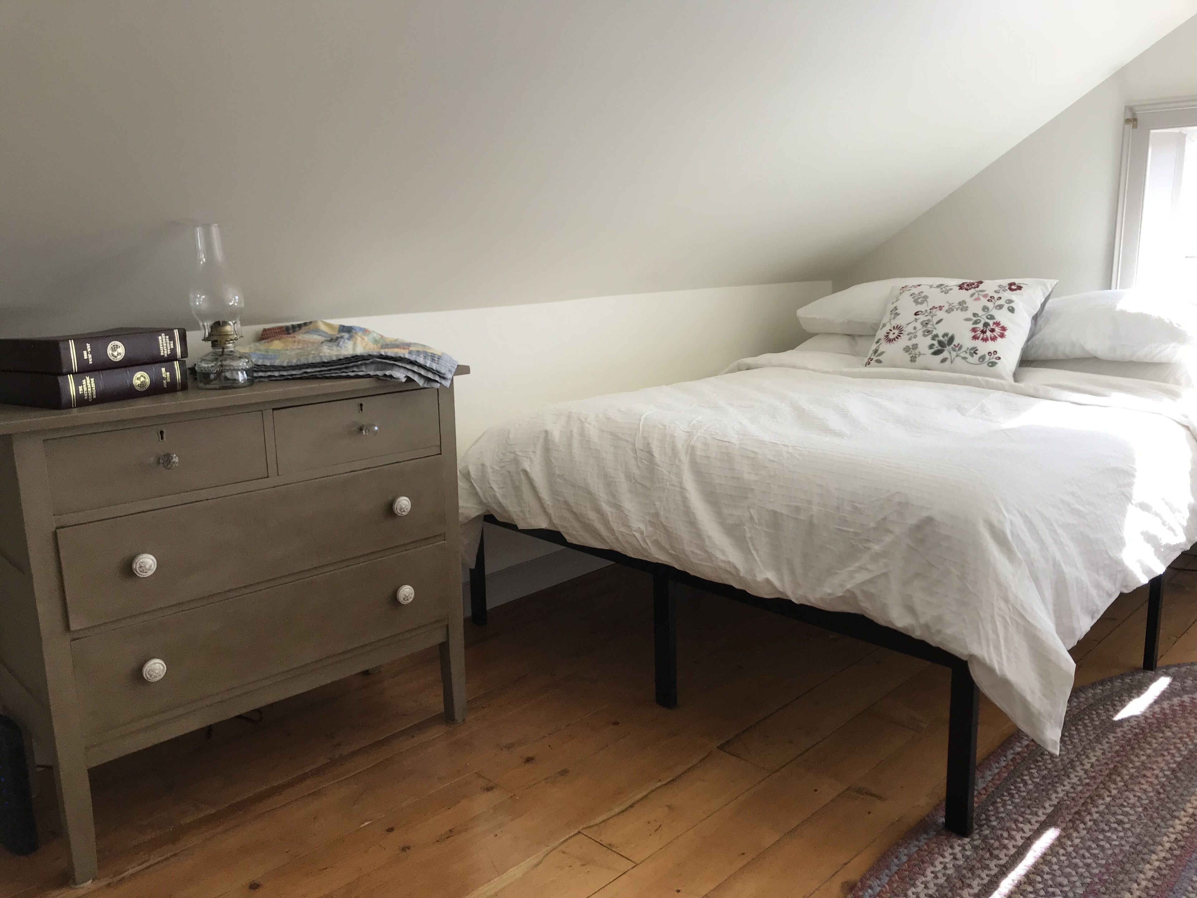 A bedroom with a bed, a dresser, and a window.