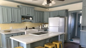 A kitchen with blue cabinets, a white refrigerator, a sink, and three yellow stools. - Hollyhock House in Spring City (Spring City)