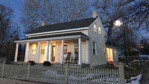A two-story house with a porch, a chimney, and a picket fence. - Hollyhock House in Spring City (Spring City)