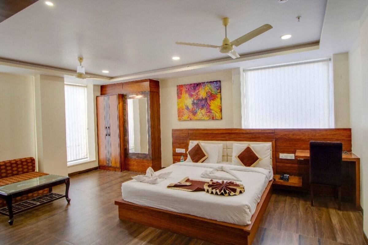 A spacious bedroom with a large bed, a desk, a sofa, and a ceiling fan.