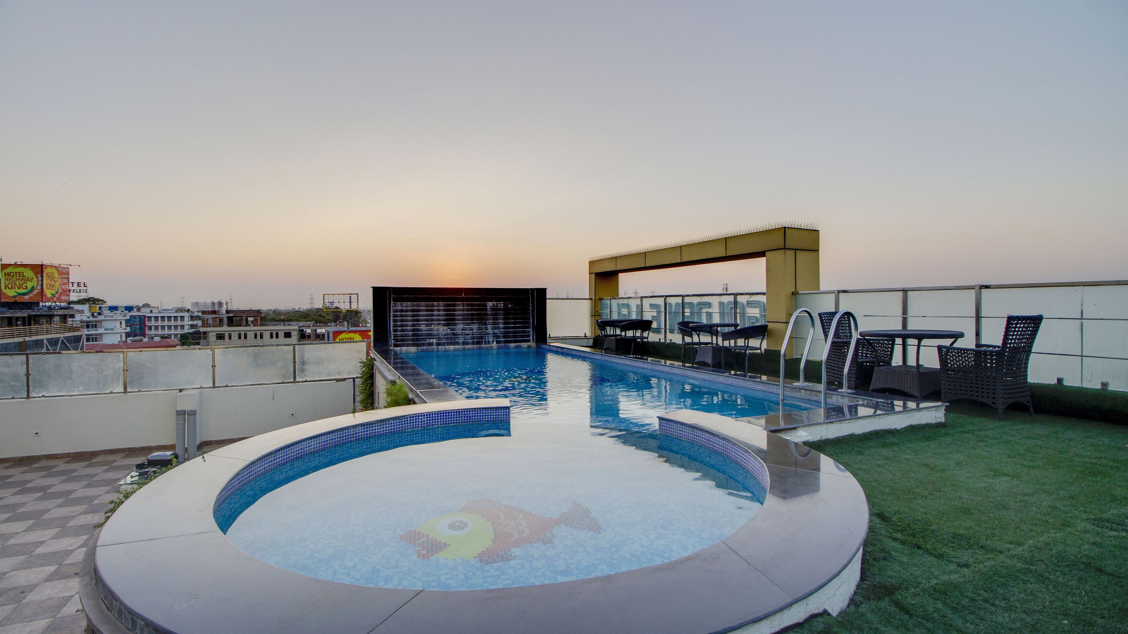 Ein Pool auf dem Dach mit einem runden Whirlpool, umgeben von Liegestühlen und einer Bar.