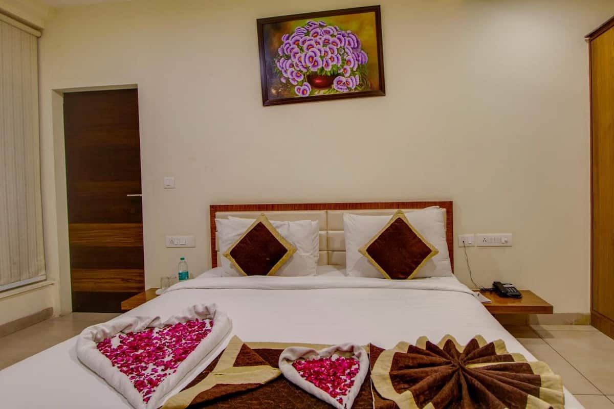 A hotel room with a bed, a nightstand, a telephone, and a painting on the wall.