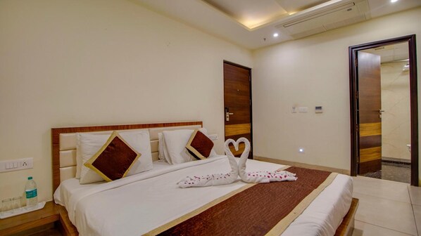Quarto de hotel com cama, cabeceira de madeira, tapete marrom decorativo e espelho na parede.