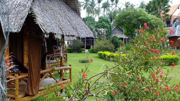 A rustic thatched-roof structure with a wooden porch, surrounded by lush greenery and flowering plants. - Lanta Marina Resort (Ko Lanta)