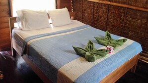 A bed with a blue and white striped bedspread, two pillows, and a green towel arrangement on the bed. - Lanta Marina Resort (Ko Lanta)