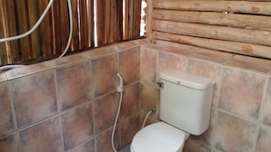 A small bathroom with a toilet, tiled walls, and a wooden slat wall. - Lanta Marina Resort (Ko Lanta)