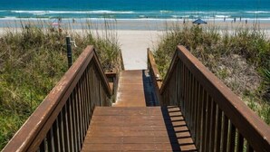 Une promenade en bois menant à une plage avec vue sur l’océan.