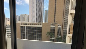 A balcony with a blue table and chairs, a view of tall buildings, and a clear sky. - Aloha Suite Near the Sea II, 3 Block Walk to Beach (Honolulu)